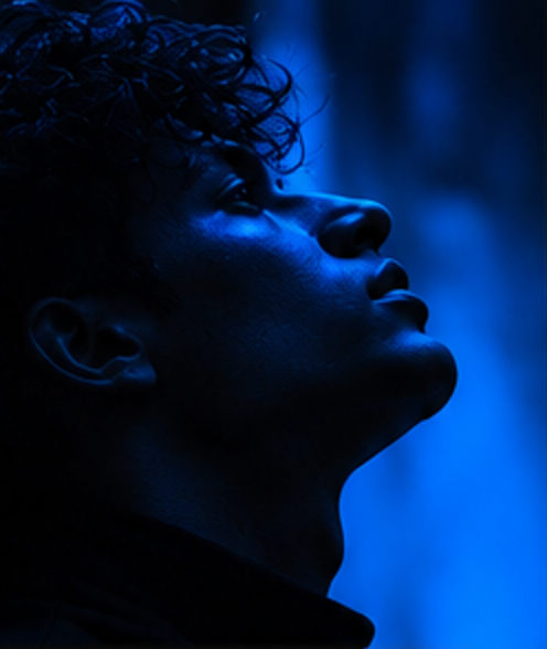 Profile of a young man looking upward in cobalt light
